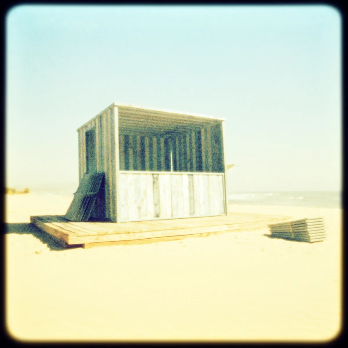 A striped wooden beach kiosk with stacked deckchairs